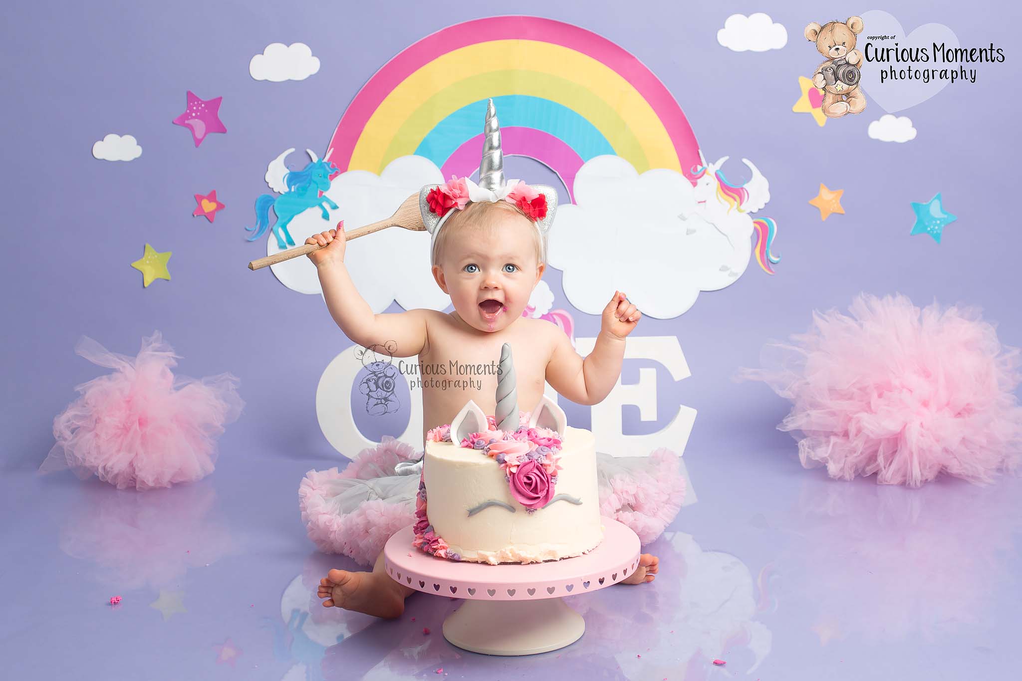 Unicorn cake smash for baby girl on purple background with a unicorn cake