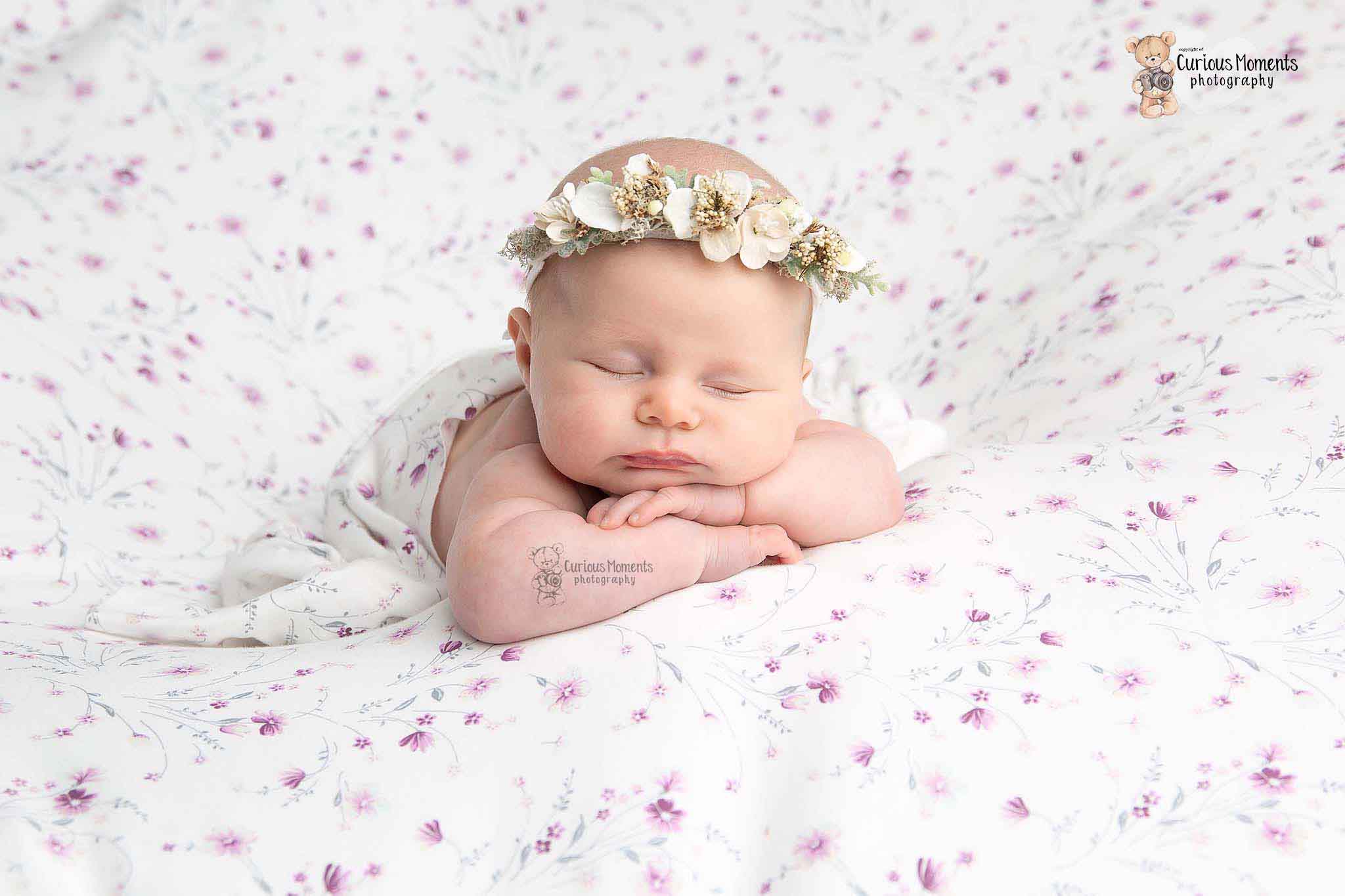 baby girl on floral background wearing white flower halo