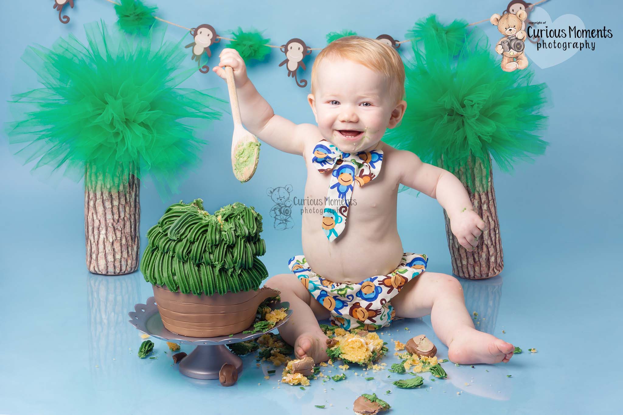 !st birthday photoshoot for little boy on blue background with ajungle Monkey themed cake smash with carmarthen photographer